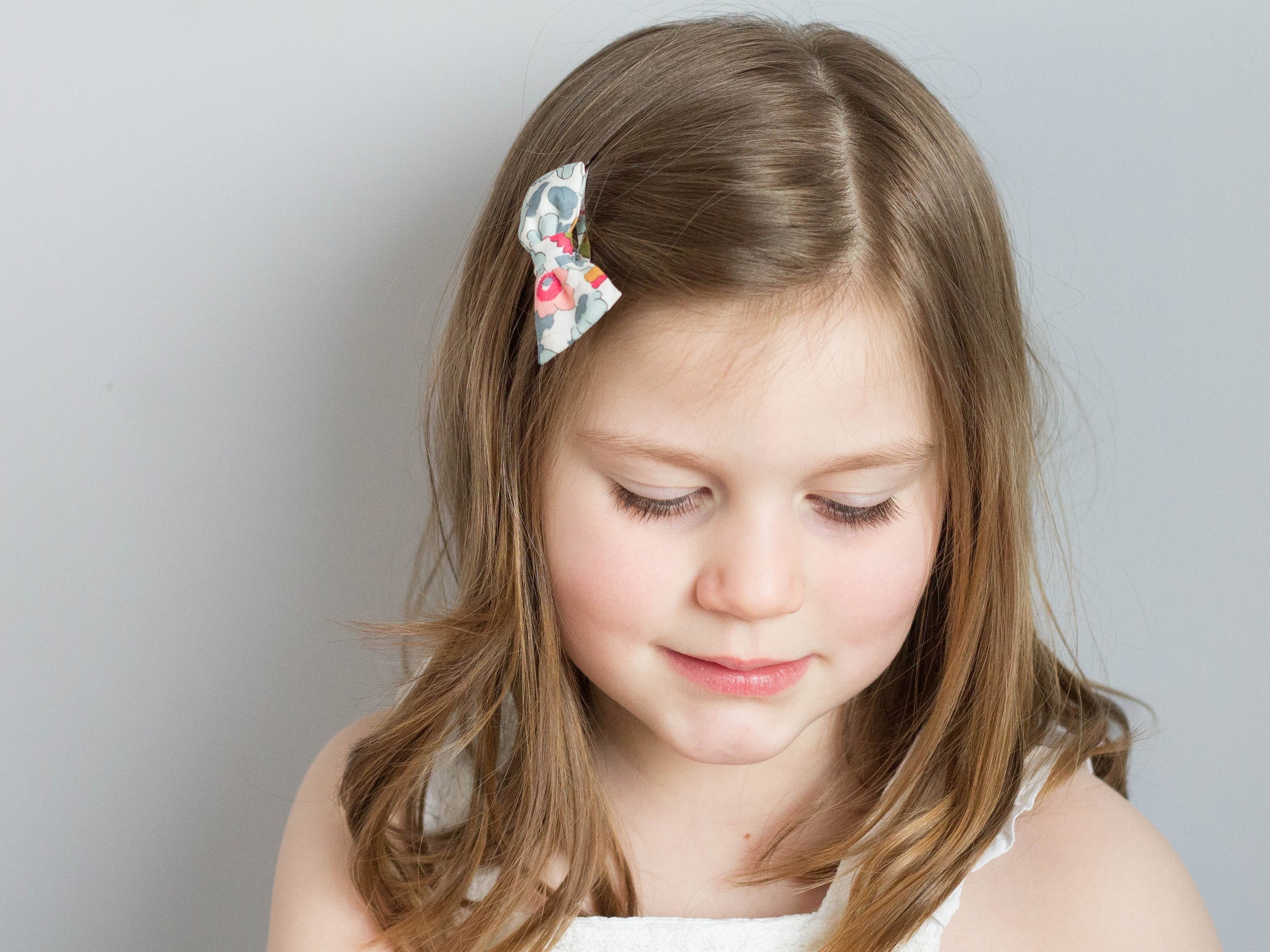 Girl wearing a Liberty London print small bow clip | Holme & Moss