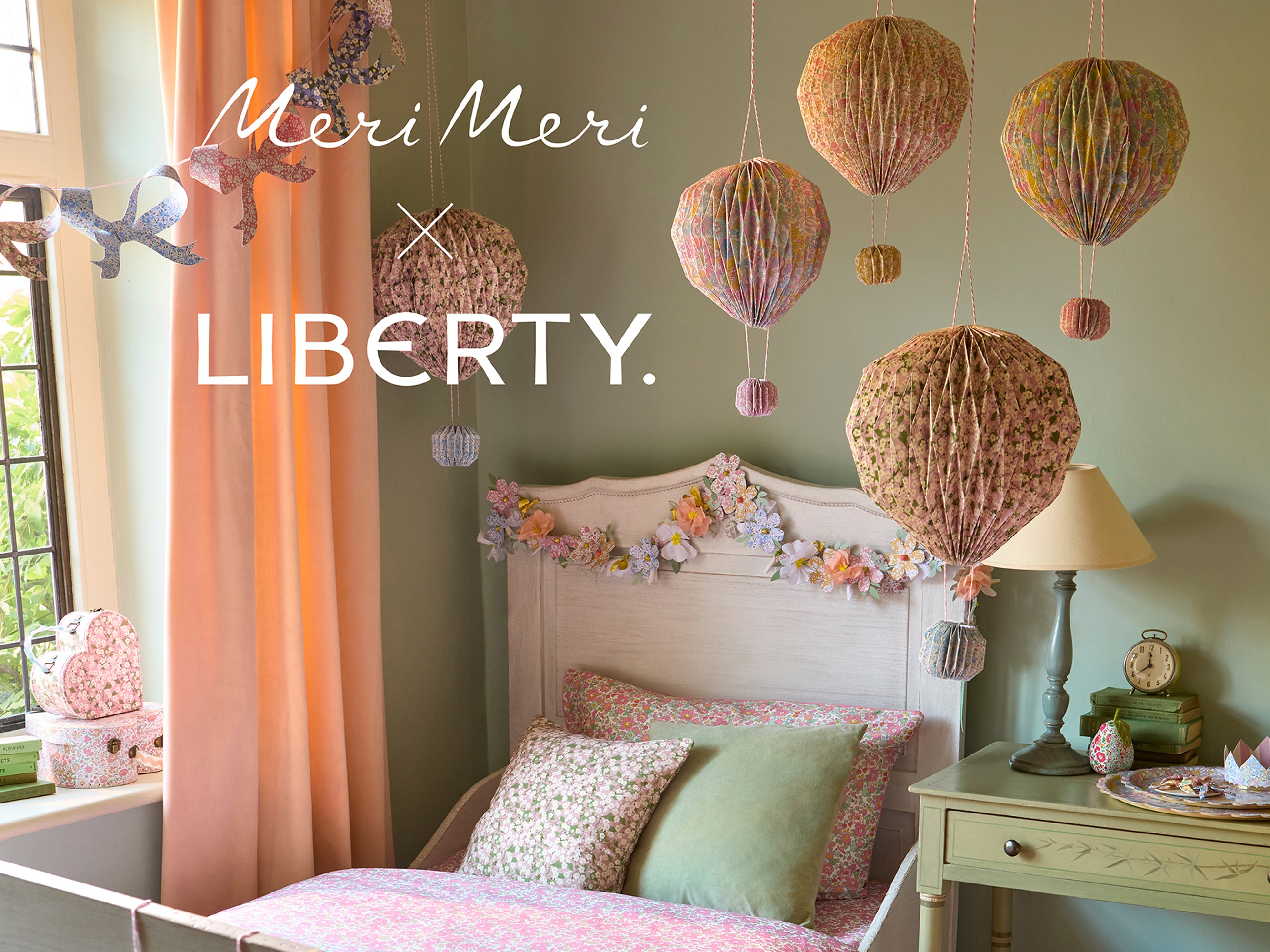 Decorative bedroom with hanging lanterns and floral garland draped on bed | Meri Meri x Liberty Paper Flower Garland | Holme & Moss