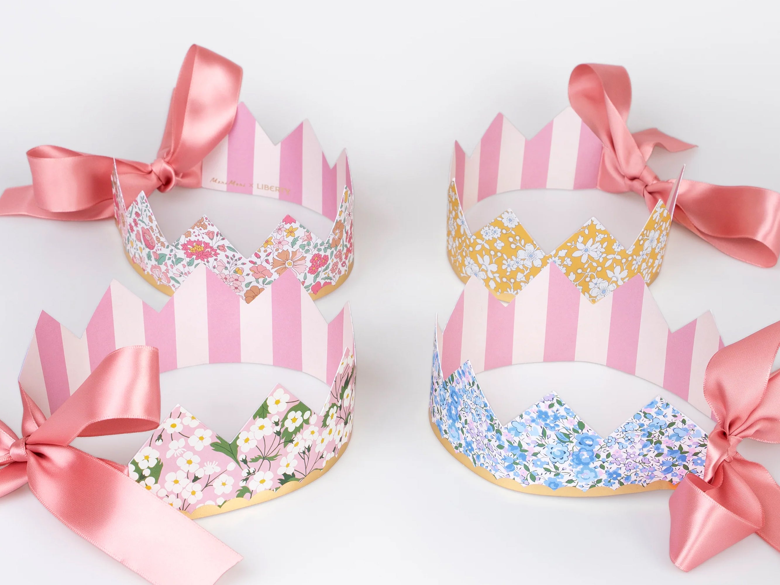Four decorative paper crowns with Liberty floral patterns and pink ribbons on a white background | Meri Meri x Liberty Party Crowns (8) | Holme & Moss