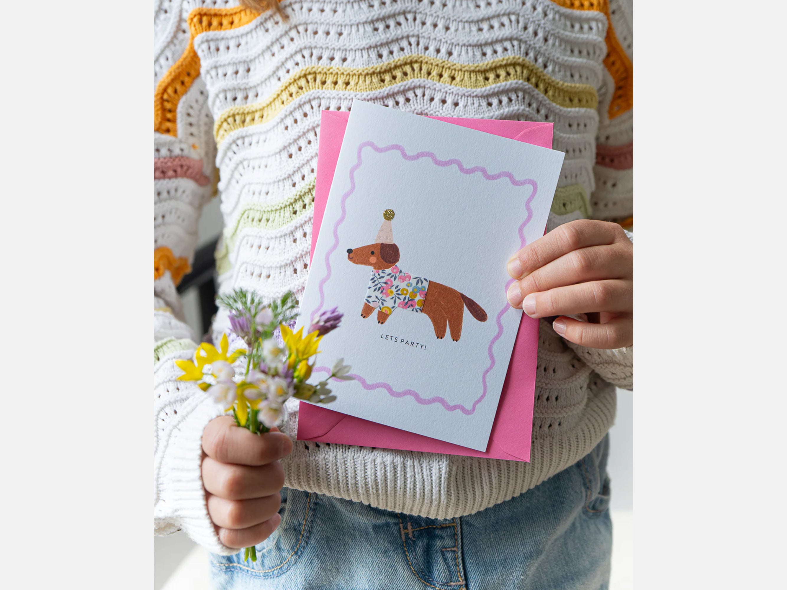 Person holding a card with a dog illustration and flowers, wearing a striped sweater | Sausage Dog Birthday Card - Liberty Wiltshire Bud Print | Holme & Moss
