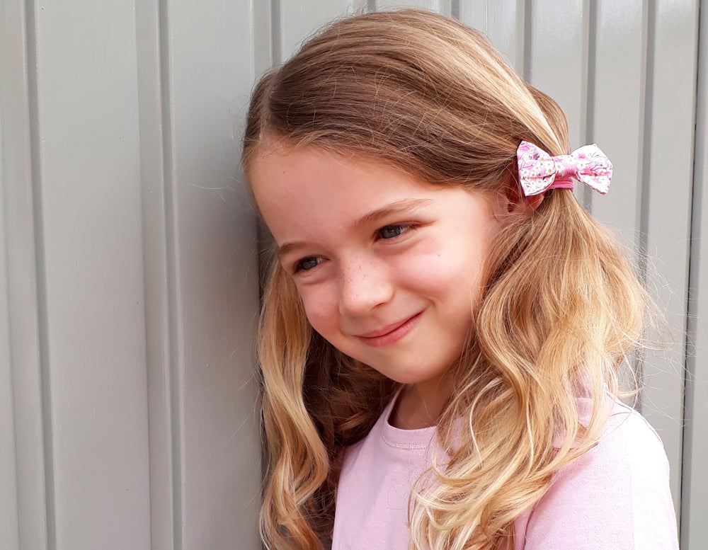 Girl wearing Liberty print bow hair band | Holme & Moss