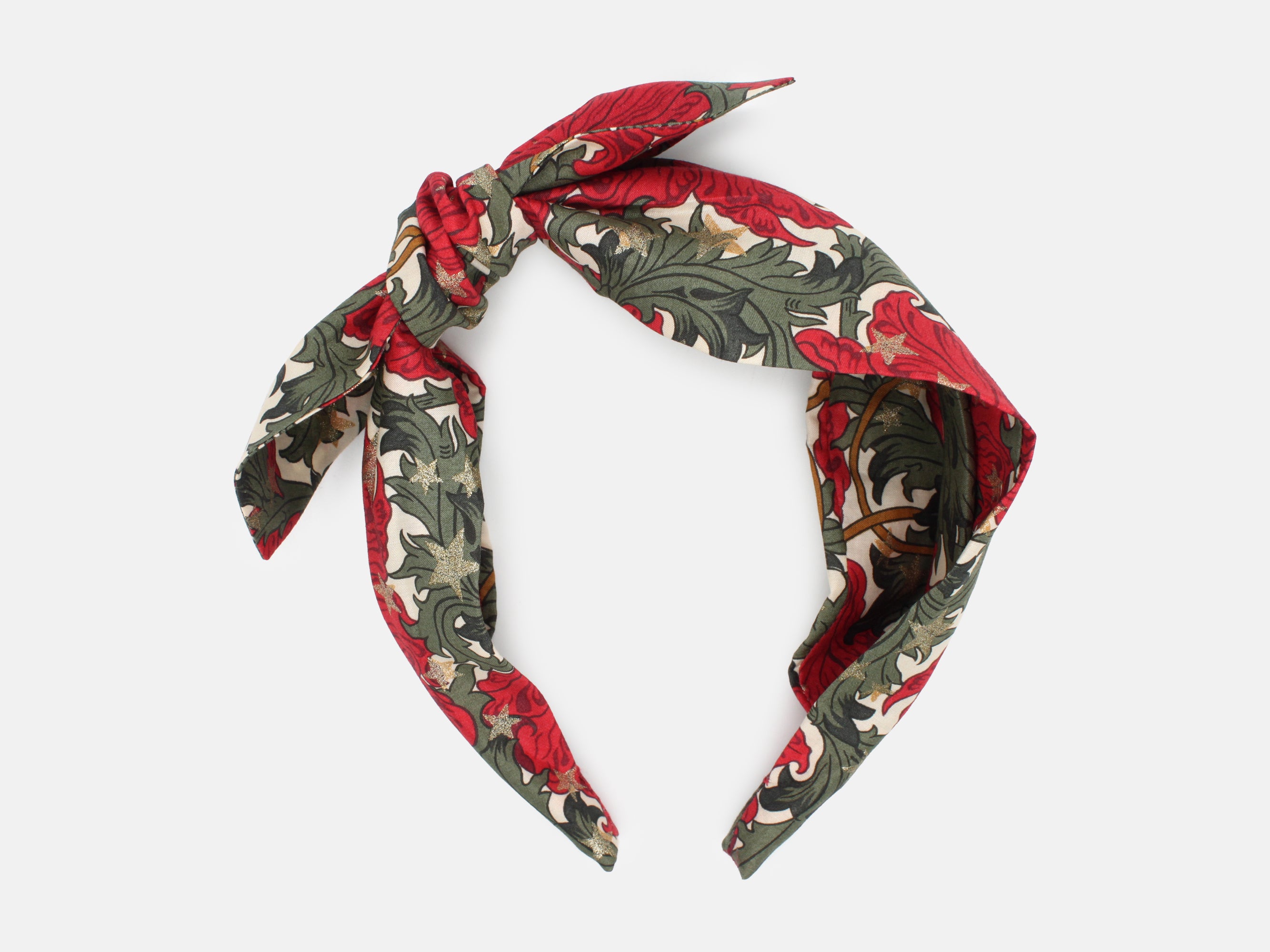 A festive side bow headband in rich red and green, scattered with shimmering gold stars | Side Bow Headband - Liberty Merry Reverie Print | Holme & Moss