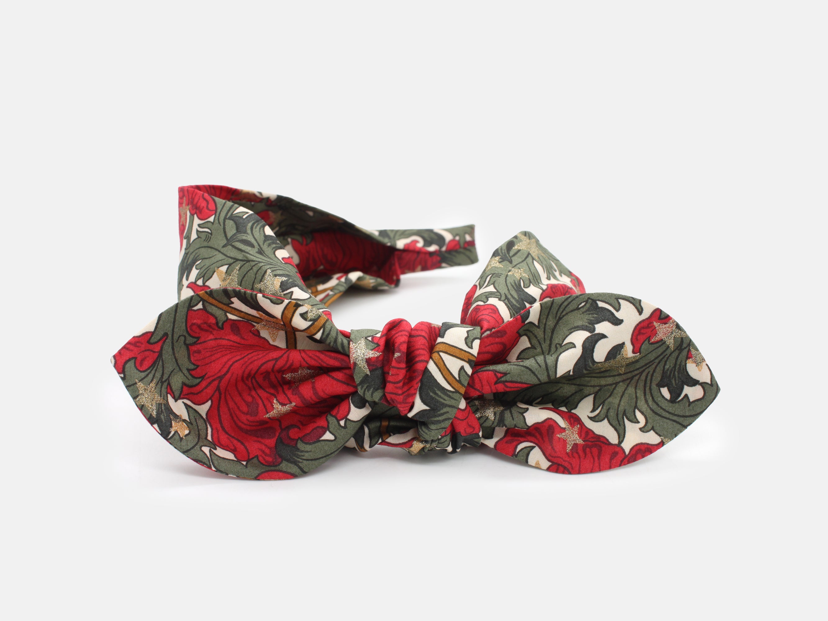 A festive side bow headband in rich red and green, scattered with shimmering gold stars | Side Bow Headband - Liberty Merry Reverie Print | Holme & Moss