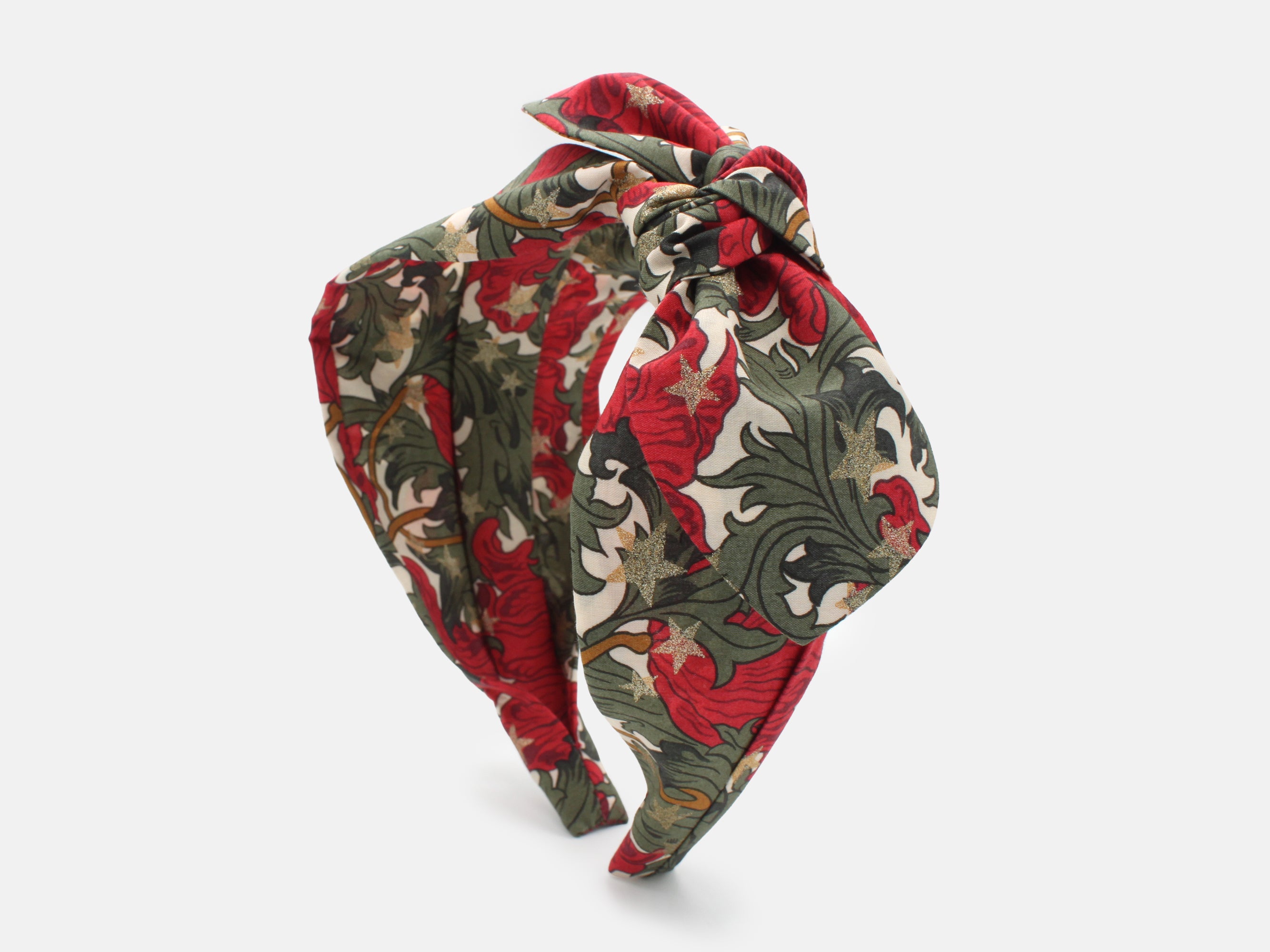 A festive side bow headband in rich red and green, scattered with shimmering gold stars | Side Bow Headband - Liberty Merry Reverie Print | Holme & Moss