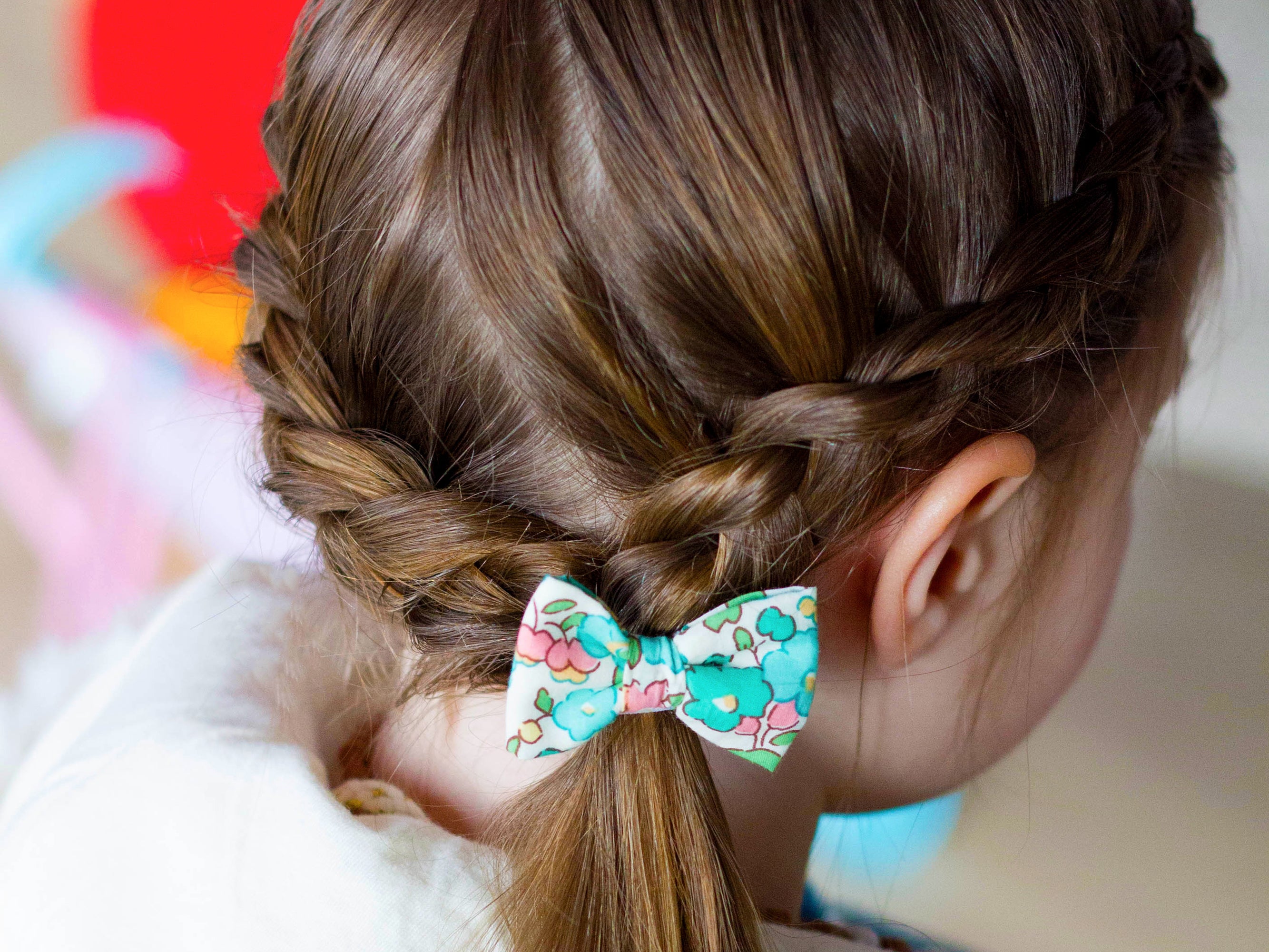Girl wearing a Liberty London print small bow hair band | Holme & Moss