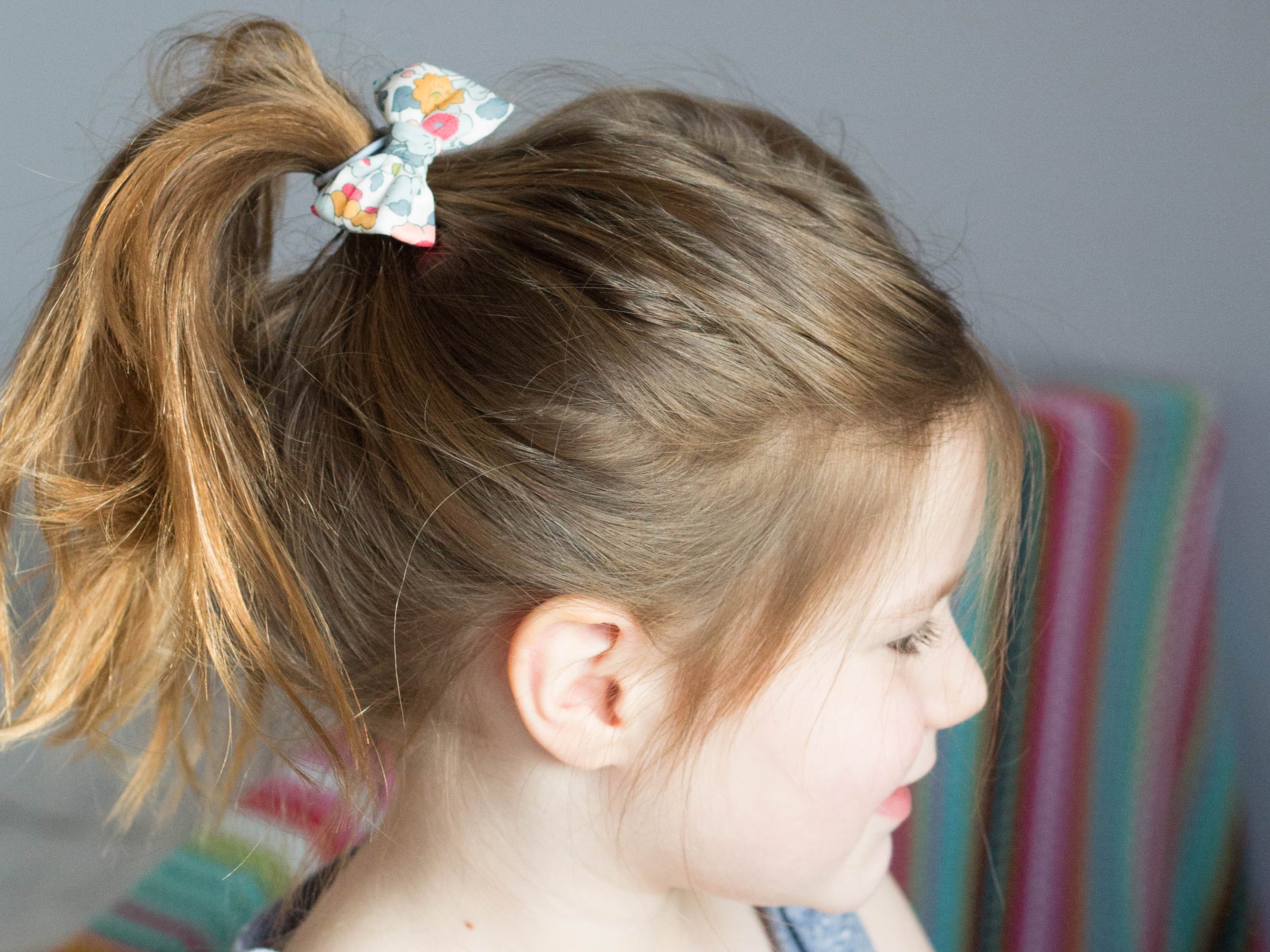 Girl wearing a Liberty London print small bow hair band | Holme & Moss